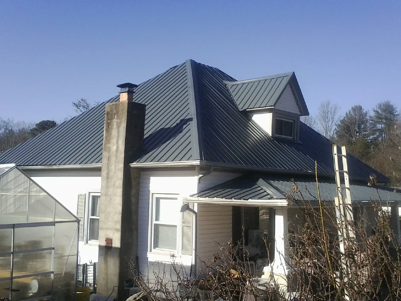 Dark blue standing seam metal roof on a white farmhouse with dormer — Slate & Tile Roof Repair by Roofing Brothers in Kersey