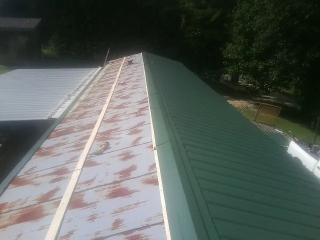 Old rusted panels beside newly installed green metal roofing — Wind Damage Roof Repair by Roofing Brothers in Kersey
