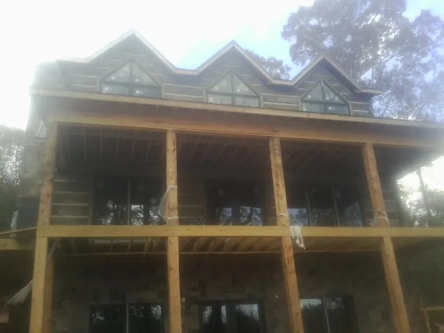 Dormers and porch framing on a large log home under construction — Roof Coating work by our crew in Kersey
