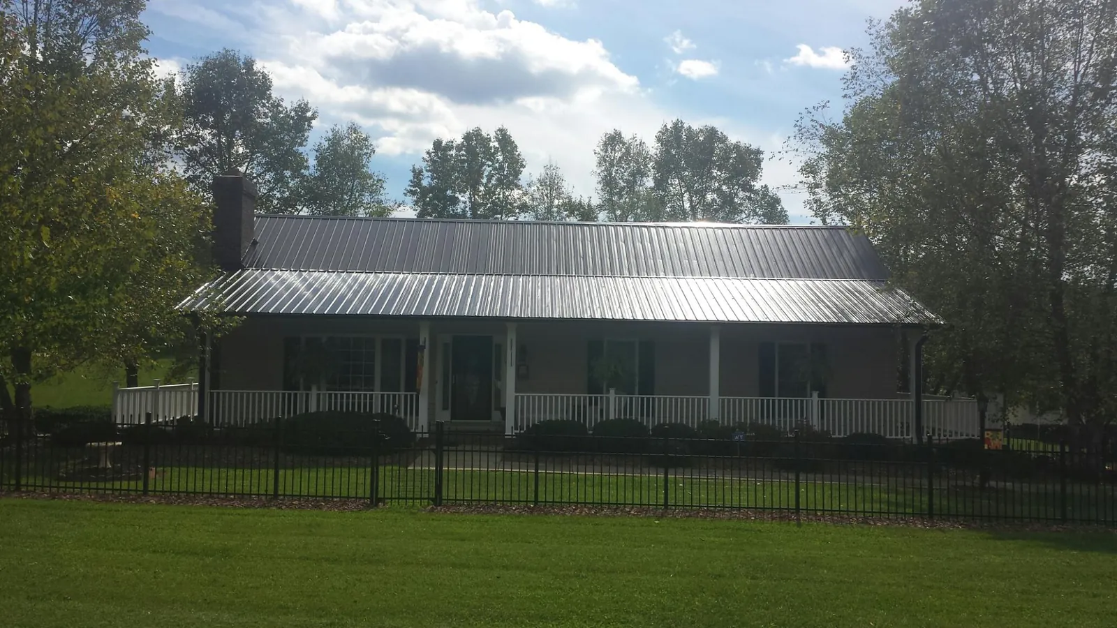 Gray metal roof on a brick ranch with a full width front porch — Gutter Guard Installation work by our crew in Kersey