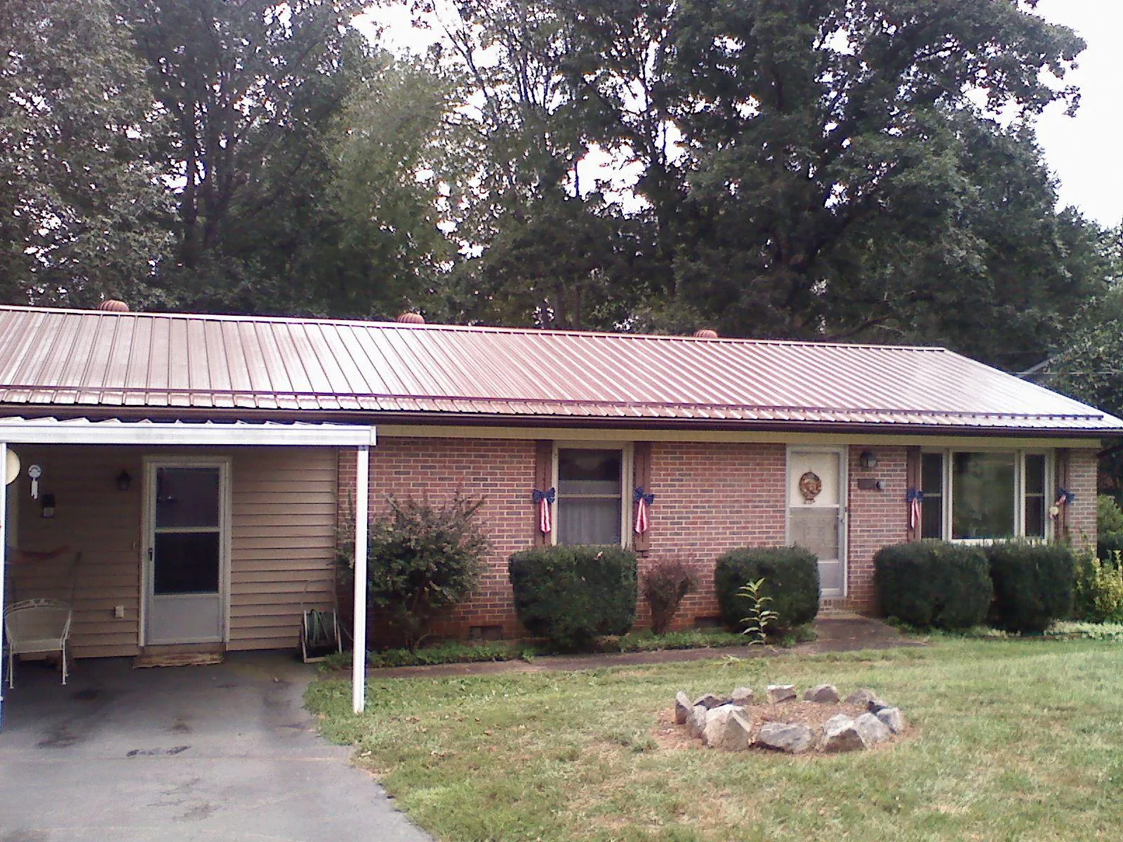 Bronze metal roof and carport on a brick ranch home — Roof Repair work by our crew in Kersey
