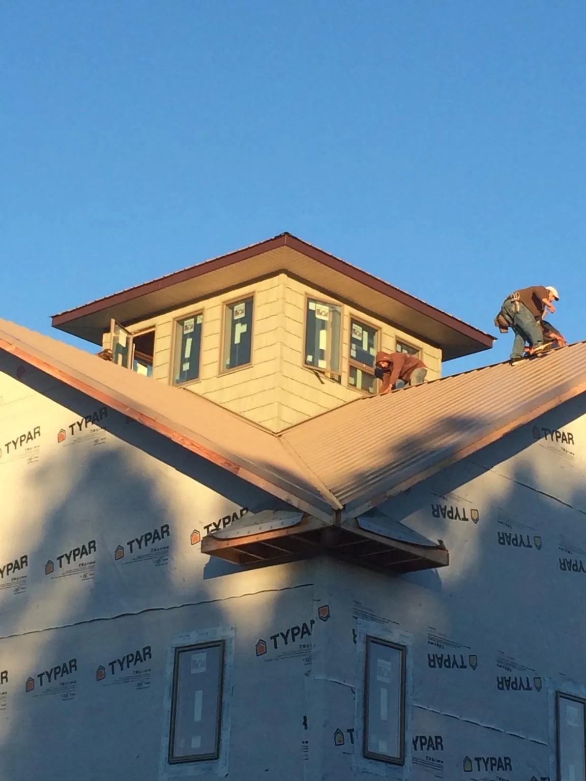 Roofers working around a rooftop cupola on a new metal roof at sunset — Roof Waterproofing in Kersey by Roofing Brothers